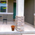 Autumn Color Leaves Small Planter with orange flowers on a porch next to a stone pillar.