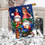 Warm Wishes Gnomes House Flag with colorful gnomes and snow scene design hanging outdoors.