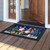 Warm Wishes Gnomes doormat with festive gnomes and Christmas trees on a wooden porch floor.