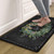 Black Home Sweet Home Wreath Comfort Mat with floral design and person's bare feet standing on it.