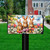 Bunny Greeting Mailbox Cover with colorful flowers and butterflies on a black mailbox post outdoors.