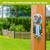 Spring Celebration Birdhouses Metal Thermometer with colorful flowers and birds on a wooden post outdoors.