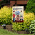 American mason jars garden flag with welcome message and floral design on a garden stand outdoors.