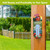 American Barn Metal Thermometer with colorful floral design mounted on wooden post outdoors.