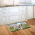 Church in Spring Doormat on wooden floor beside white kitchen cabinets and sink area.