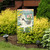 Spring Adirondack Chair Garden Flag with white chair, tulips, and Welcome Spring text on stand.