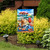 Beach Day Garden Flag with vibrant beach scene, colorful umbrella, and refreshing summer drinks displayed outdoors.