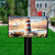 Lighthouse At Sunset Mailbox Cover with red, white lighthouse and sailboat on rocky shoreline at sunset.
