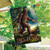Believe Bigfoot House Flag with brown Sasquatch and Believe text on a garden background.