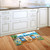 Beach Chairs Doormat on wooden floor in front of white kitchen cabinets and sink area.