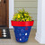 Large blue Star Spangled Planter with red rim and star pattern holding colorful flowers.