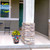 American Bloom medium planter with yellow flowers on a porch with stone pillar and green door.