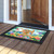 Spring Has Sprung Sign Doormat with colorful floral design and decorative black border on wooden porch.