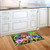 Pansy Trio Doormat with colorful pansy flowers on a green background on wooden kitchen floor.