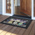 Lavender and Daisies doormat with purple flowers and black border on a wooden porch floor.