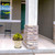 Tan and red floral medium planter with yellow flowers on a porch next to a pillar.
