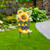 Yellow rain boots with sunflowers and daisies on a metal stand in a garden setting outdoor decor.