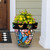 Large Checkered Butterflies planter with colorful butterflies and flowers on a porch with green siding.