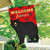 Red plaid house flag with black bear and "Welcome Friends" on a wooden pole outside home.