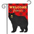 Black bear on red burlap garden flag with "Welcome Friends" text, findme, hanging on metal stand.