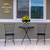 Geometric Floral Medium Planter on black metal table between two chairs on concrete patio outside window.