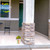 Spring Stripes Planter with yellow flowers on a porch next to a pillar and chair.