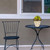 Small Tan Floral Planter on a black metal table next to a matching chair outdoors.