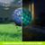 Blue and white scalloped mosaic gazing ball with solar LED lights on a stand outdoors.