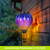 Solar balloon lantern with blue, purple, and orange hues hanging from a chain outdoors.
