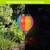 Multicolor Solar Balloon Lantern with solar panel on top, hanging outdoors with vibrant red, yellow, blue, purple.
