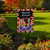 Hocus Pocus garden flag with colorful border and witch design on a lawn with flowers.