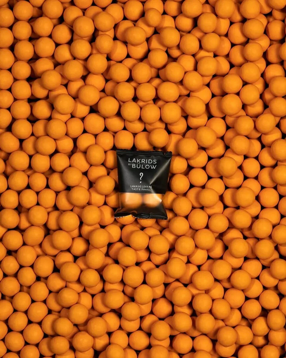 En ukendt LAKRIDS LOVERS Taste Panel-smag omgivet af orange chokoladeovertrukket lakrids