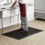 Worker standing on a 3' x 5' black rubber anti-fatigue floor mat with beveled edge in a commercial kitchen wash area.