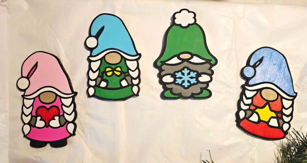 Set of four wooden gnome figurines featuring colorful hats and winter designs, displayed as handcrafted Christmas decorations.