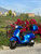 2020 Vespa GTS 300 HPE in Matte Blu Vivace with color-matched top box and black trim, parked in front of bright pink flowers and a scenic California hillside.