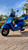 A Matte Blue 2020 Vespa GTS 300 HPE parked on a brick walkway, showing the LED headlight, chrome mirrors, red front suspension spring, and the integrated rear storage box with a passenger backrest.