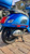 Close-up of a 2020 Vespa GTS Super 300 HPE in Matte Blue showing the chrome exhaust, Michelin tire, and GTS Super badging.