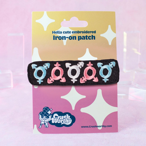Trans Icon Patch by Crushworthy – pastel pink, pastel blue, and white on a black base with 5 trans symbols on an iron-on backing!