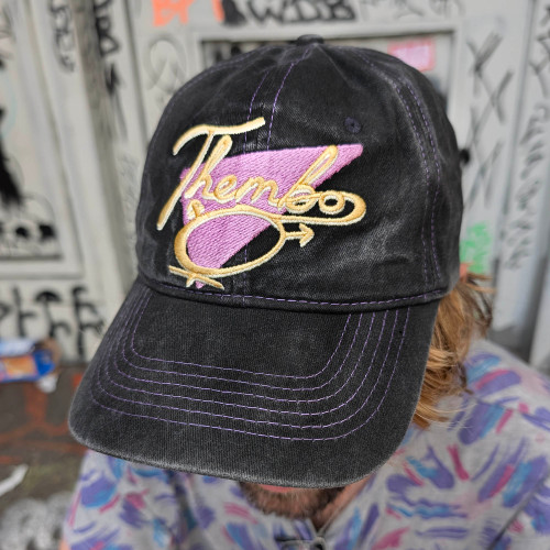 Thembo Throwback Cap by Crushworthy - Fun retro embroidery that says "Thembo" with a trans symbol below it, embroidered directly onto an acid wash black baseball cap.