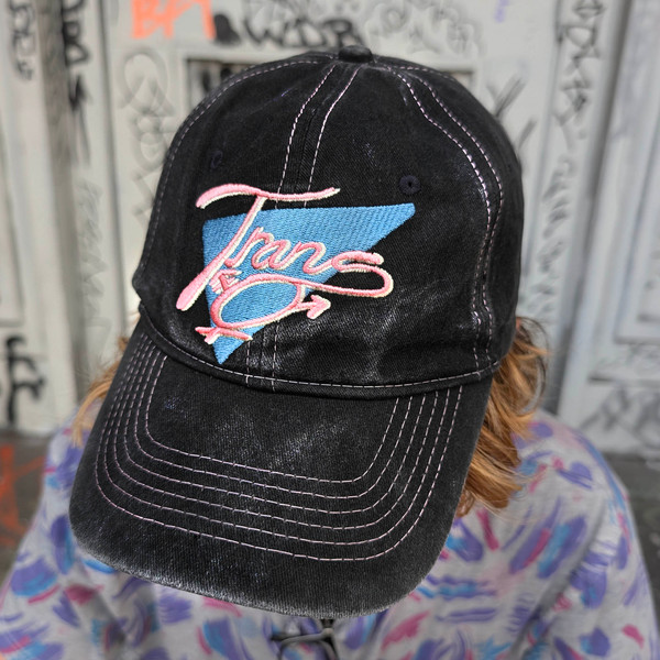 Trans Throwback Cap by Crushworthy - A fun retro embroidered design that says "Trans" with the trans symbol below it on an acid wash black baseball hat.