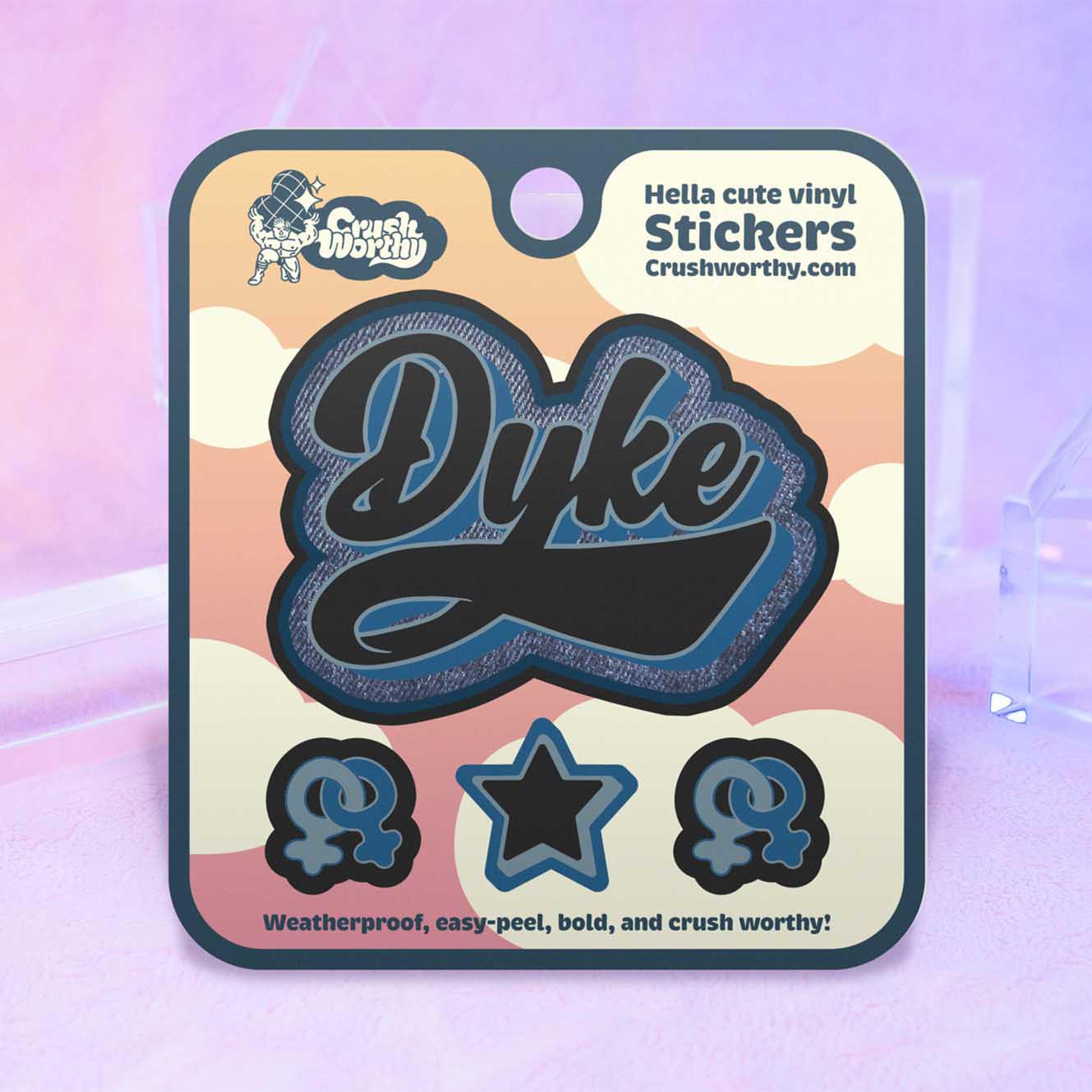 Dyke Varsity sticker sheet by Crushworthy - A blue and black denim textured sticker that says "Dyke" in varsity style lettering. Comes with 2 mini lesbian symbol stickers, and a matching star sticker!