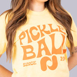 Close up front view of Pickleball Central's Heritage Pickle-ball Groovy Front Logo Unisex T-Shirt on a female model in the color Banana Cream.