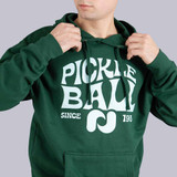 Close up front view of the Pickleball Central Heritage Pickle-ball Groovy Front Logo Unisex Hoodie on a male model in the color Alpine Green.