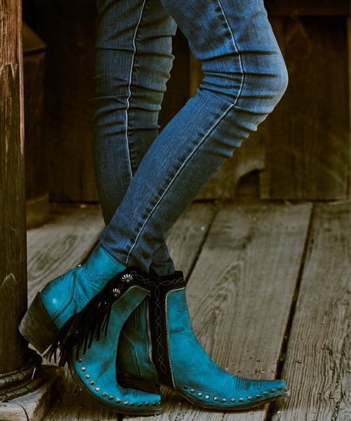 Step up your boot game with this season’s popular mid-calf length. Double D Ranch’s Apache Kid Boot adds a few more inches, a little more coverage, and a lot more style points.  Hand crafted in calfskin with contrast trim and sassy fringe, but it is the turquoise studded conchos that take this boot over the top.  

Features:

Toe: snip 

Leather: calfskin with suede contrast

Heel: tall riding 

Nail heads

Navajo style conchos

Self lacing and fringe
