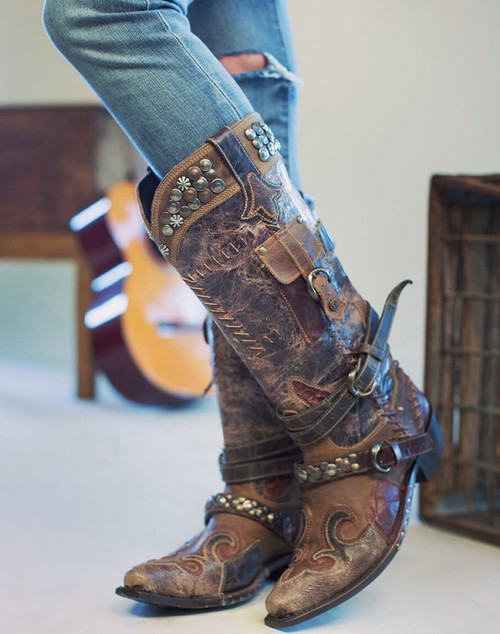 The Frontier Trapper Boot  has a rustic look with  the wear-and-tear holes and patching, which comes from a combination of 5 worn and perfectly distressed leather. The side-pocket and the bullet keeper on the back were an afterthought to the original design. Perfect for the modern-day "trapper gal" to store her cell phone, credit cards, and a little ammo.  Load'em up and get going!
Snip Toe
Cowgirl Heel
16" Shaft including heel
2" Heel
Distressed Leather
Metal Stud Embellishment
 
