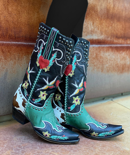 “I’m walkin’ here!” The namesake boots of the Midnight Cowboy collection have a little bit of everything that influenced us from the movie: from the signature color scheme of blacks and retro teal to the whimsical designs of hand-stitched florals and love birds, to the sneak peek of pony hide on the heel paying homage to the film’s iconic suitcase.