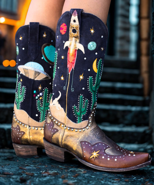 Meet the Galactic Buckaroo by Old Gringo Boots! The details are out of this world...With stars seriously aligned and a black suede leather upper, copper vamp, and scenic views of a desert in the wild wild west this boot is truly from outer space...Studs and crystals add sparkle that light up any occasion while colorful planets and spacecrafts create adventures to come. 