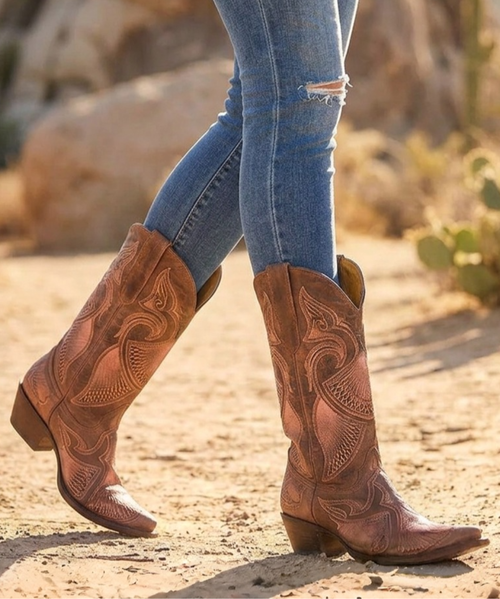 These boots are a beautiful blend of classic western shape and feminine, artistic detailing ?✨

Crafted from rich brown leather, they feature a softly distressed finish that adds warmth and character. The silhouette is timeless with a mid-calf shaft, snip toe, and a stacked angled heel, giving them that authentic cowboy boot structure.

What truly makes them stand out is the intricate wing-inspired embroidery that flows across the shaft and vamp:

Curving, feather-like patterns create movement and elegance

Soft blush-pink tones are layered into the design, adding a subtle pop of color

Fine stitching and delicate detailing give the boots a light, almost ethereal contrast against the rugged leather

The pull tabs and clean topline keep them functional, while the overall design feels romantic, elevated, and uniquely western.

These boots strike the perfect balance between earthy and feminine—ideal for pairing with dresses or denim when you want something classic with a soft, standout twist