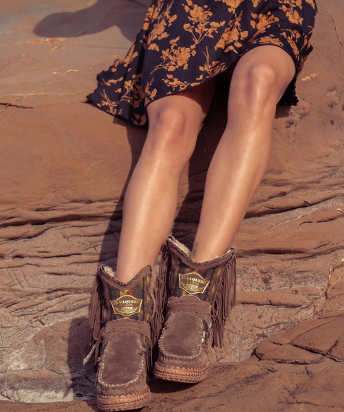 The Arya Nantuk Silverstone Brown leather fringe boot features a 2 3/4" internal wedge, soft fringe, beautiful leather side tabs, and thick hand-stitched toecaps—a hallmark of the El Vaquero brand. Crafted from a stunning combination of premium calf suede and Native American-inspired cotton fabric, it's lined with soft boiled wool fur.

2 3/4" internal wedge
Vintage treatment
100% Suede and tribal fabric
Fur lining
Handcrafted stitching
Metallic details 100% nickel free
Rubber sole