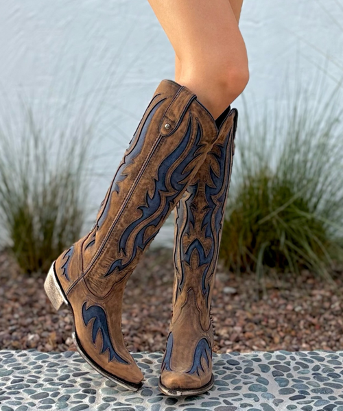 Three Words: To. Die. For. ?
We are head over heels for these stunning Liberty Black Boots! Crafted with richly distressed canela beige leather, they feature azul blue inlays and a chic snip toe that blends timeless Western charm with modern, fashion-forward flair.

The 17" tall silhouette elongates the leg beautifully, while the soft vintage-treated leather gives them that perfect broken-in feel from the very first step. Finished with an easy walking heel, these boots are the kind you’ll wear year-round — pair them with dresses, denim, festival fits, or date-night looks for a show-stopping style moment.

These beauties aren’t just boots… they’re a whole vibe. Get ready for compliments.

Measurements:
Shaft Height: 17"

Shaft Opening: 14.5" circumference

Heel Height: 1 3/4"

Toe: SNIP

Width: Standard